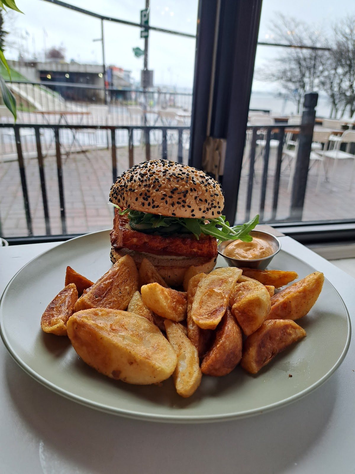 Un burger et des pommes de terre en quartiers, devant la fenêtre qui donne sur le fleuve